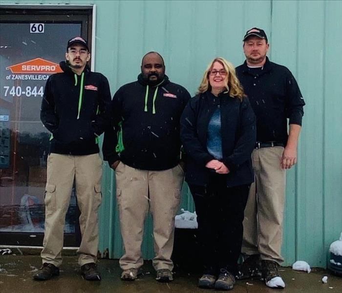 Photo of entire group standing in front of building wearing black